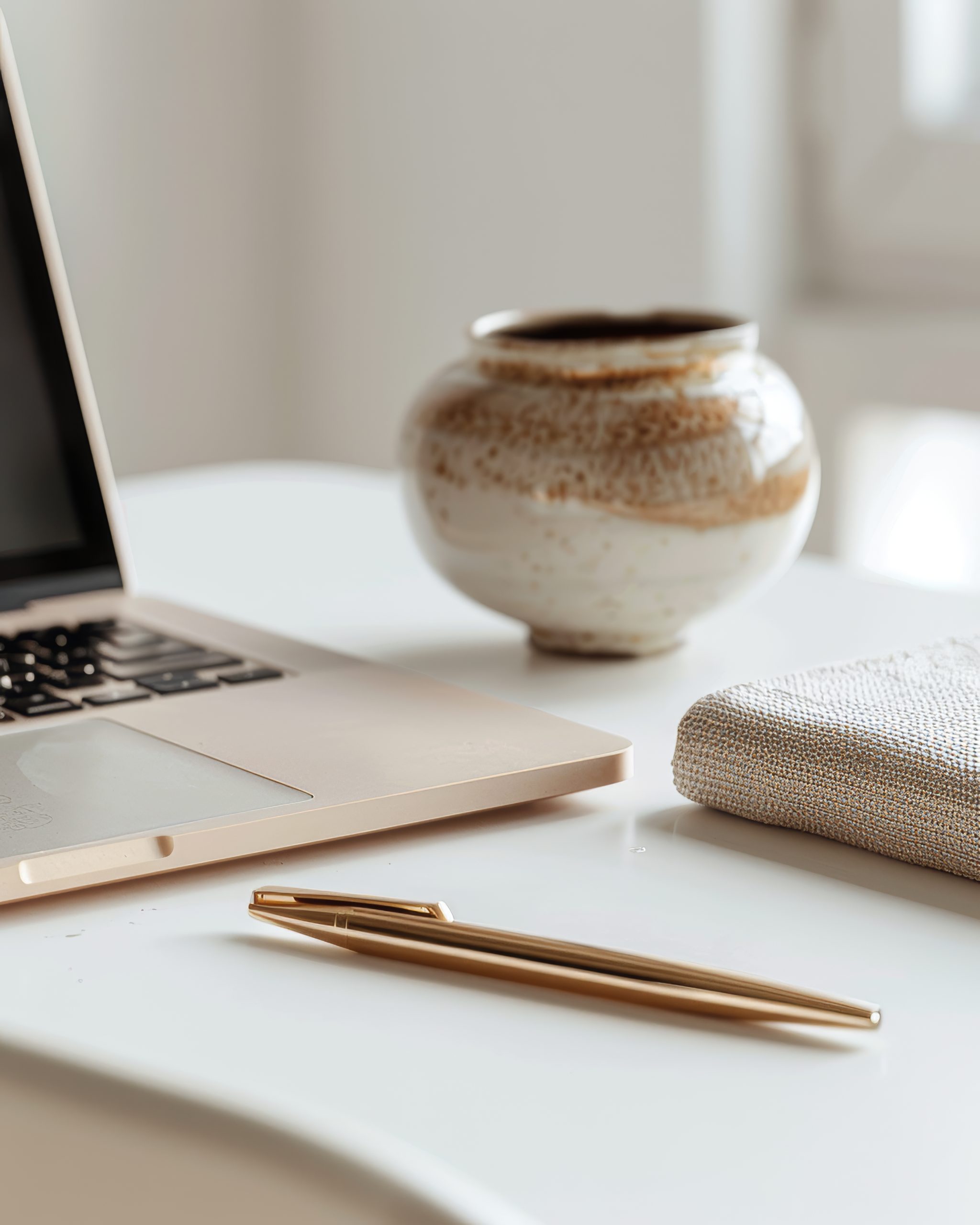 macbook pro with gold pen and book and round white and gold vase on a desk creating an idea about page seven marketing strategies.