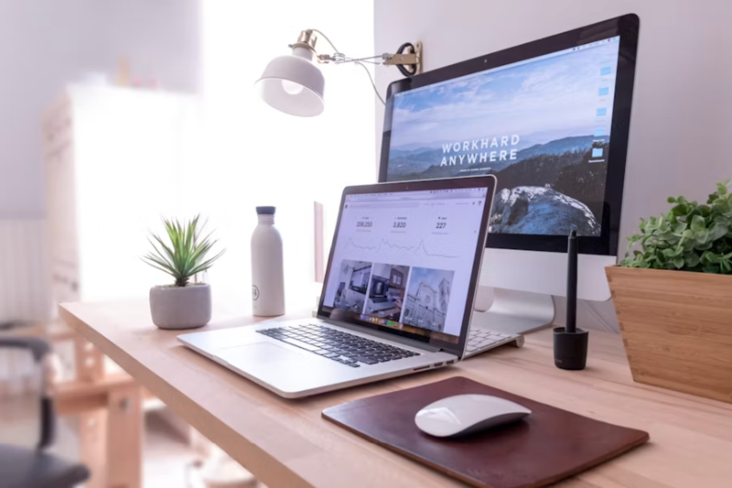 a laptop and desktop monitor ona desk in a sun lit office representing page seven marketing agency.