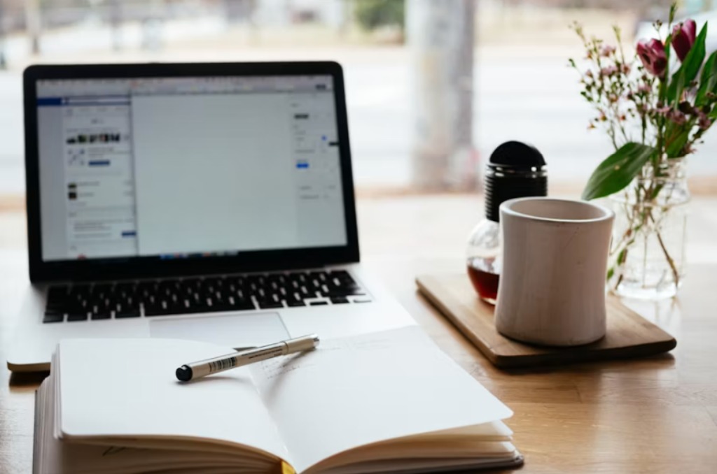 laptop with a book and coffee at a desk with notes about seo for retail and consumer brands at page seven marketing.